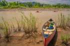 USA, New Mexico, Rio Grande River. Empty canoe on riverbank and kayakers on river. Art Print